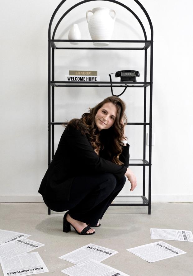 Ashley Hoover smiling beside a shelf with a Welcome Home book